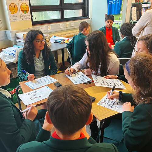 Students around a desk writing notes