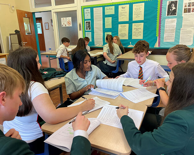 Students around a desk with booklets